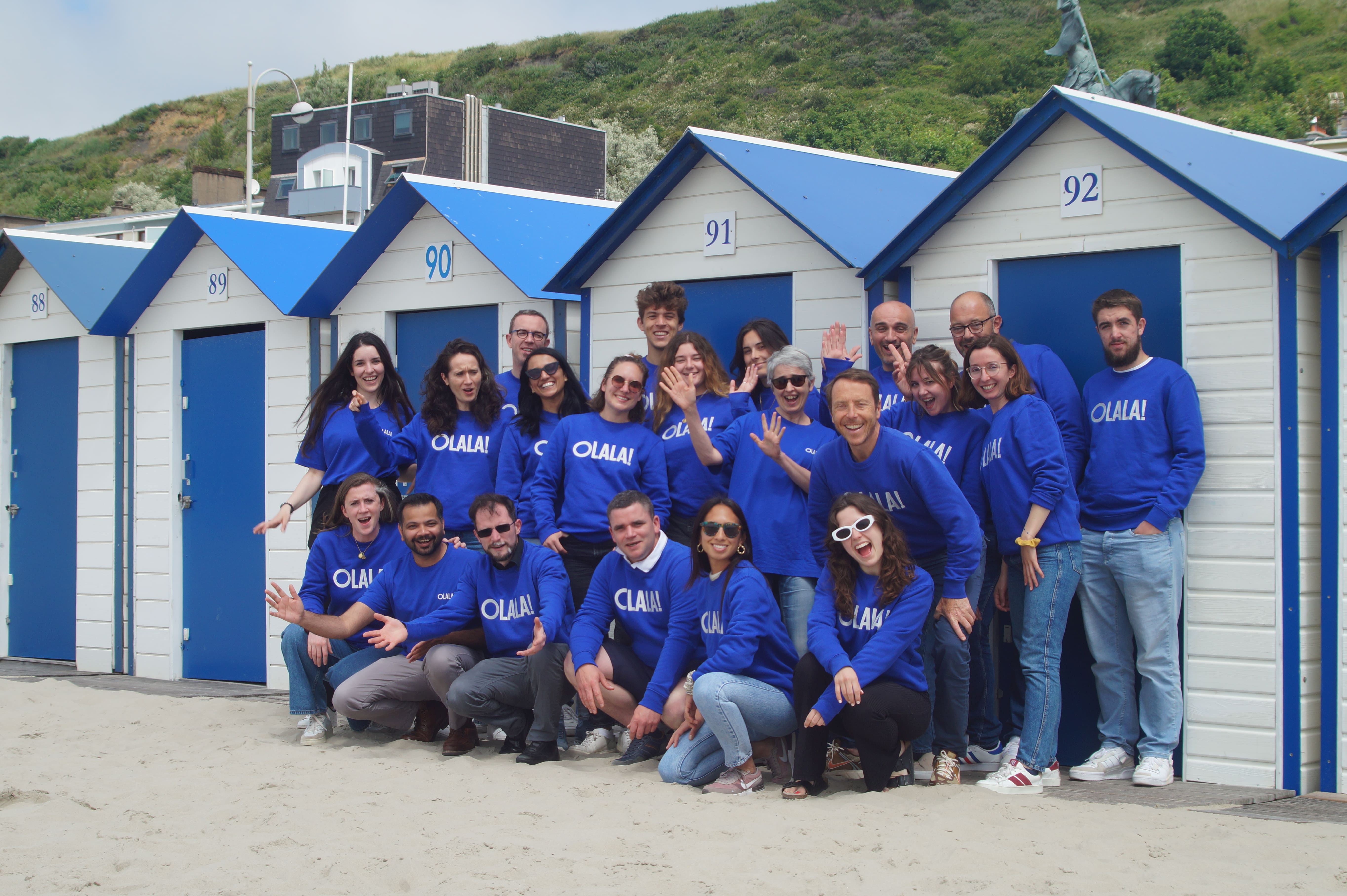 Happy team of work colleagues at a beach seminar, standing together in front of beach houses, enjoying the sunny day